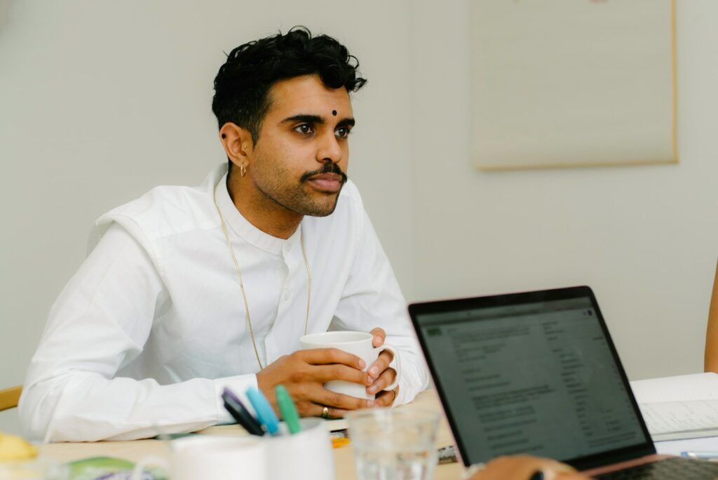 a man sitting in front of a laptop computer and showing up tips for a successful job interview